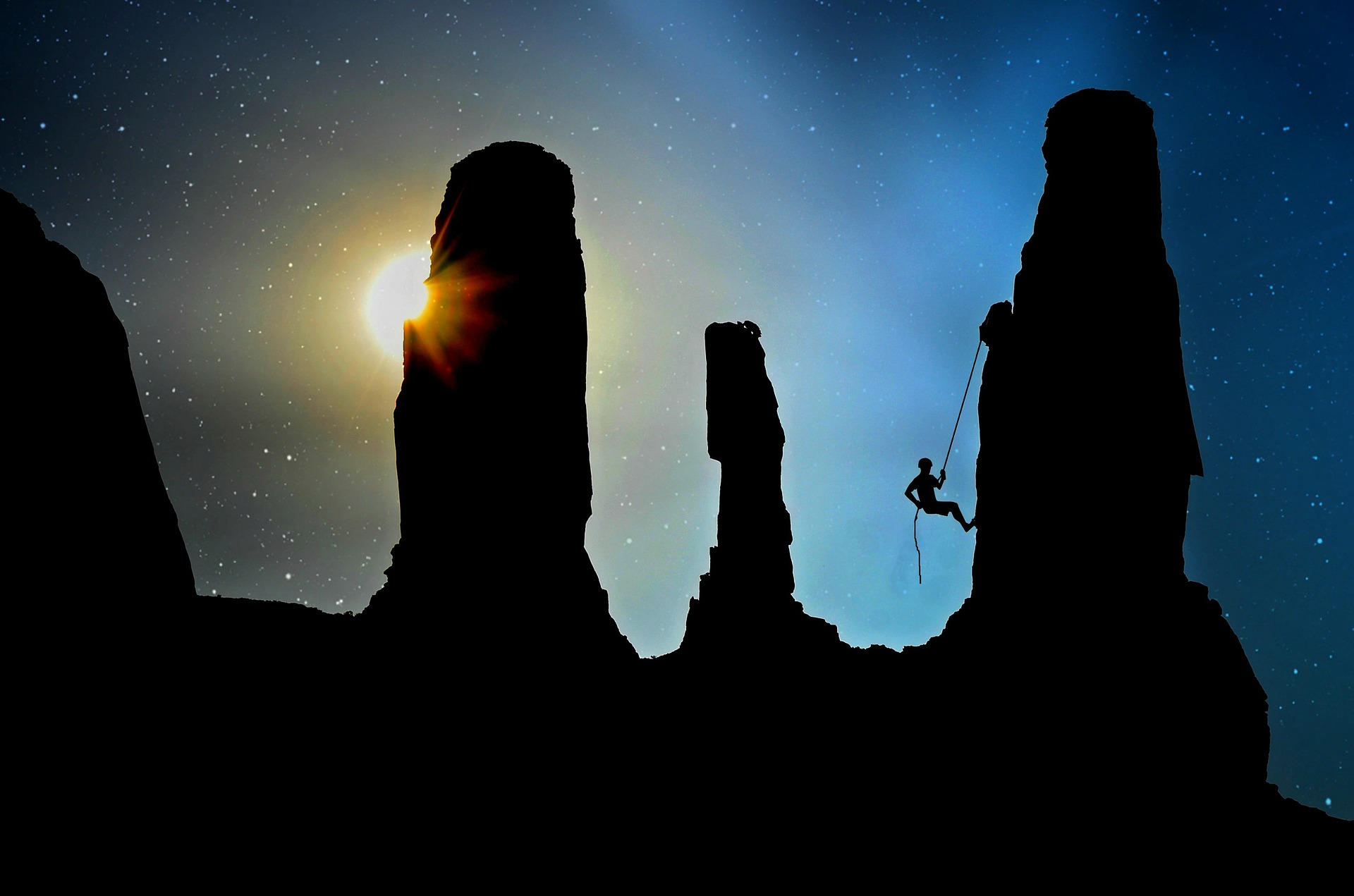 A silhouette of a person climbing against a starry sky